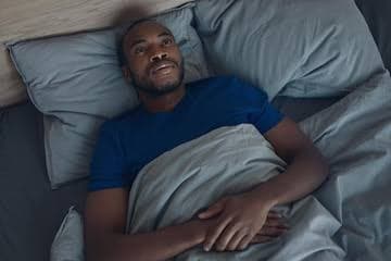 Person lying awake in bed at night unable to sleep