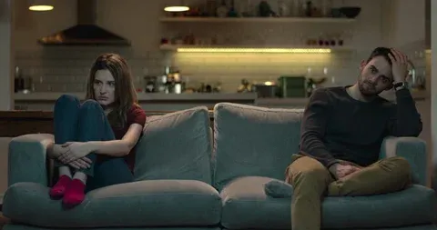 Couple sitting apart on a couch in Plymouth, Minnesota