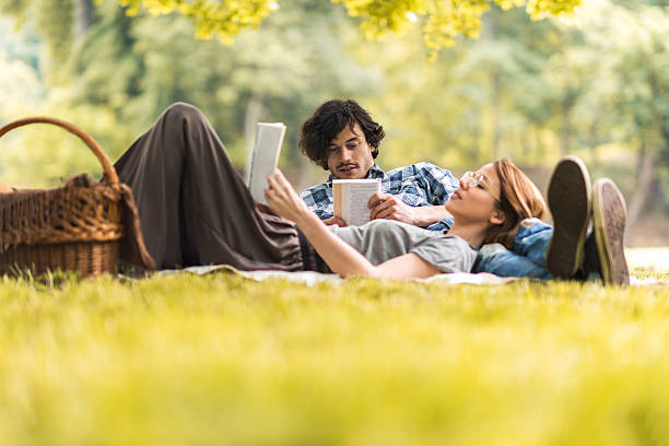 Couple relaxing together outdoors, one reading and one journaling